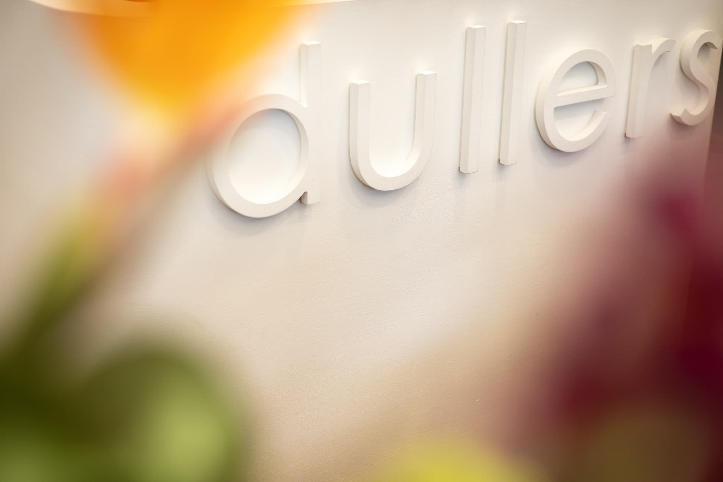 De dullers-letters op de muur van de salon, omlijst door verse bloemen